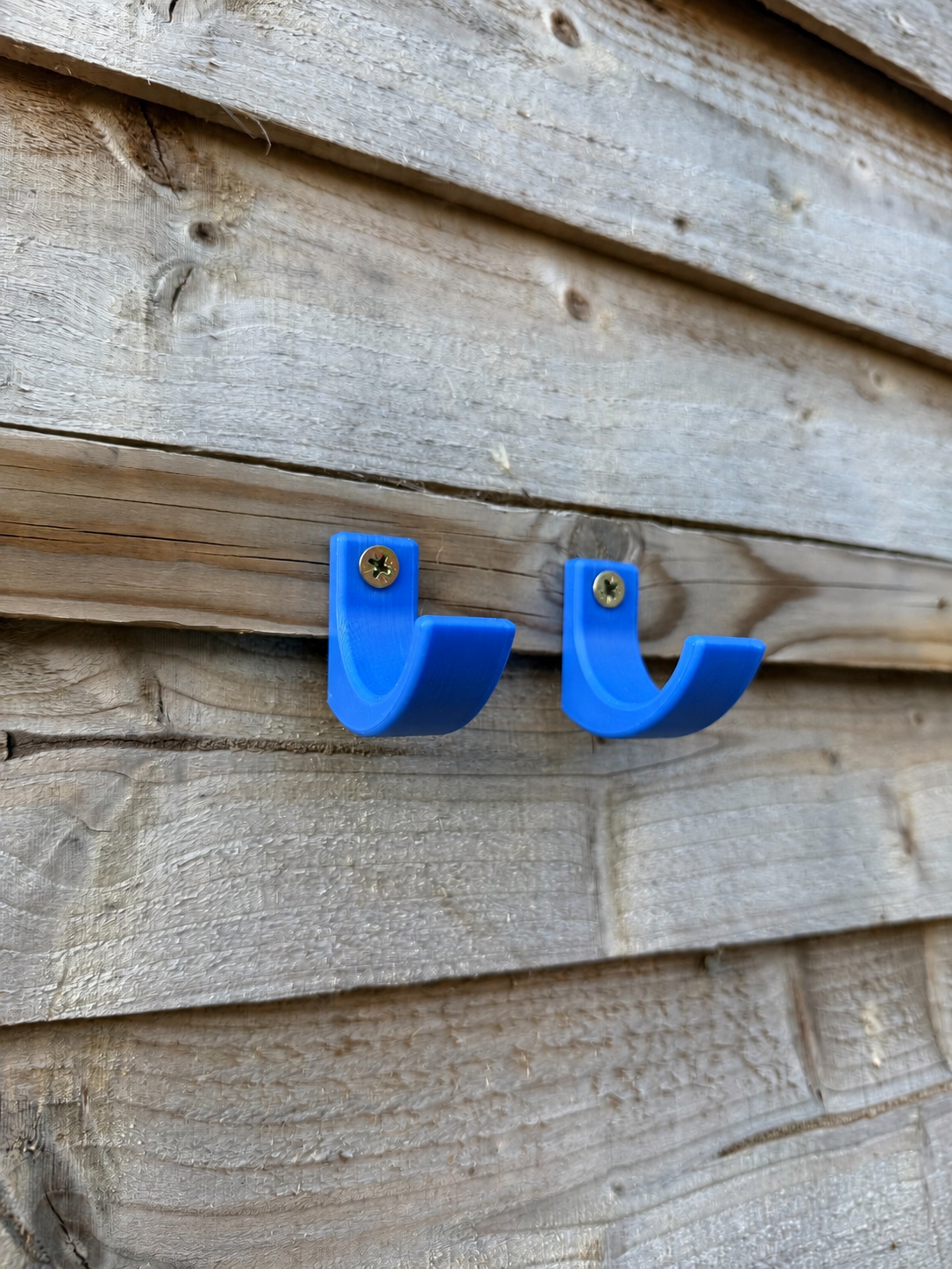 Pair of blue 20mm garden tool hooks mounted on a wooden wall
