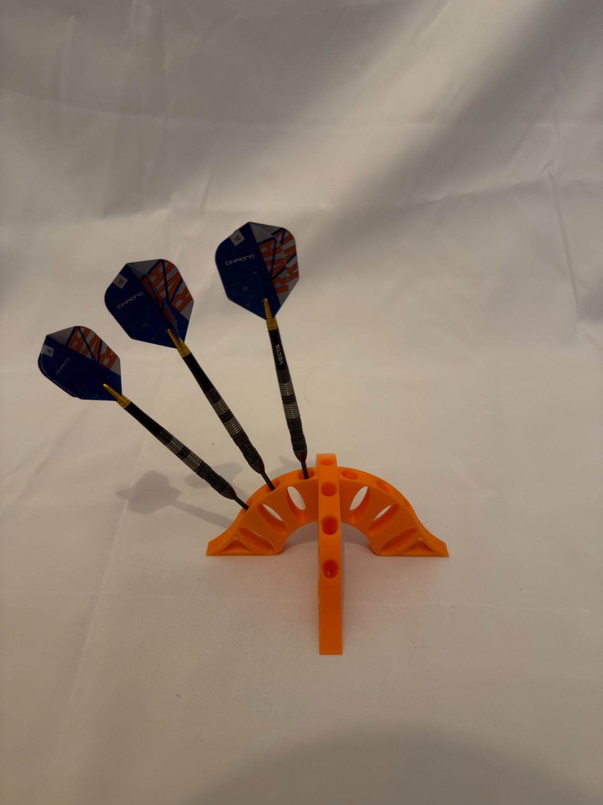 Dartboard Setup at Home: Height, Distance and Storage 2 Orange interlocking curved dart stand shown with three demonstration darts
