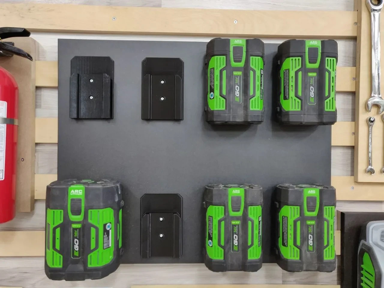 Garden Tool Storage Ideas for Small Sheds 2 EGO batteries and empty black battery holders arranged on a wall-mounted board